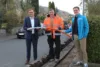 Drei Menschen stehen auf einer Straße, mit einem Glasfaserkabel in den Händen.