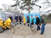 Eine Gruppe von Menschen mit Schaufeln vor einem Haufen Erde