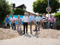 Menschen stehen mit Spaten vor zwei Hügeln Erde