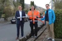 Drei Menschen stehen auf einer Straße, mit einem Glasfaserkabel in den Händen.