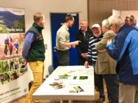 Herren werden vor einem Plakat beraten