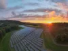 Sonnenaufgang über einem Solarpark im Wald Michelbach an einem leicht bewölkten Morgen.