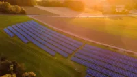 Große Photovoltaikanlage auf einem grünen Feld, bestehend aus mehreren Reihen von Solarpaneelen