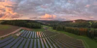 Eine große Solaranlage mit mehreren Reihen von Solarpaneelen, die sich über ein weites, grünes Feld erstrecken