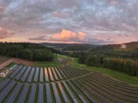 Eine große Solaranlage mit mehreren Reihen von Solarpaneelen, die sich über ein weites, grünes Feld erstrecken